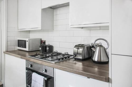 a kitchen counter with a stove and a microwave at 'Number 11' Central Colchester - Super Convenient 2 x Double Bed 1 x Single Bed Cottage PLUS Office & Garden, 8 min walk Nth Station & Town Ctr, 2 min walk local shops & restaurants in Colchester