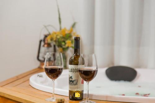a bottle of wine and two glasses on a table at Chalés Recanto da cachoeira in Monte Verde