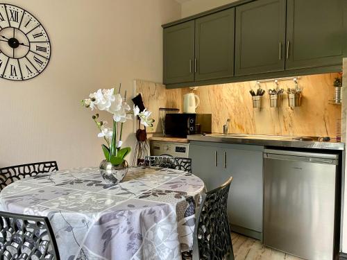 Una cocina con una mesa con un jarrón de flores encima. en Residence Soleil des Thermes 2, en Le Mont-Dore