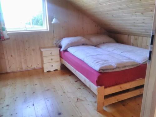 a bed in a wooden room with a wooden floor at Domek Bażant in Kołczewo