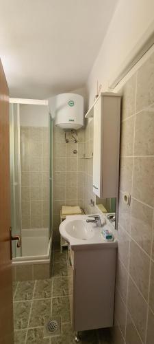 a bathroom with a sink and a shower and a tub at Adria Arba Apartments in Rab