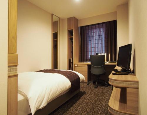 Cette chambre comprend un lit et un bureau avec un ordinateur. dans l'établissement Hotel Fukuoka Garden Palace, à Fukuoka