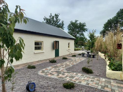 a white building with a garden in front of it at Mary's Bespoke Cottage in Killarney