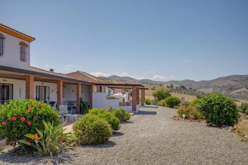 una casa con un camino que conduce al patio delantero en Finca Feliz Andaluz, en Álora