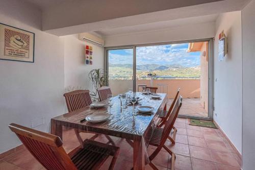 une salle à manger avec une table et des chaises et une grande fenêtre dans l'établissement Attique à Banyuls - vue mer et montagne, à Banyuls-sur-Mer