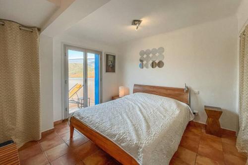 a bedroom with a bed and a large window at Attique à Banyuls - vue mer et montagne in Banyuls-sur-Mer