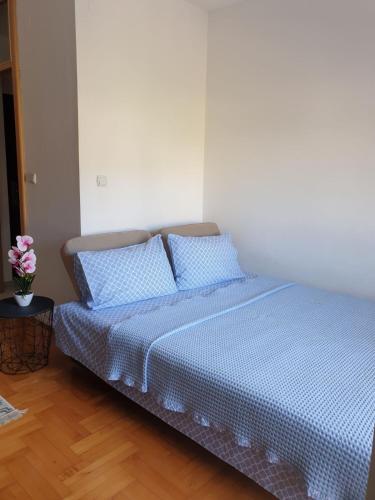 ein Schlafzimmer mit einem Bett mit blauer Bettwäsche und einer Vase aus Blumen in der Unterkunft Izdajem studio - apartman in Igalo