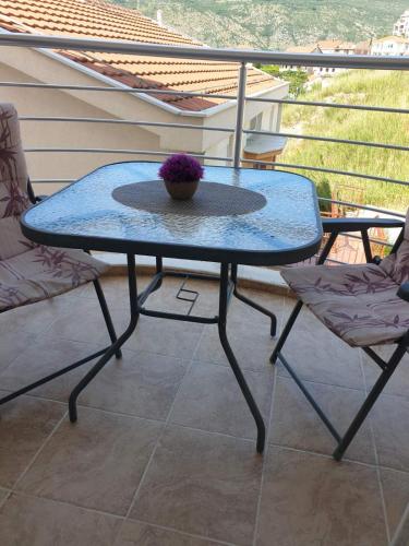 einen Glastisch und zwei Stühle auf dem Balkon in der Unterkunft Izdajem studio - apartman in Igalo
