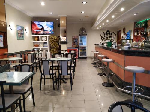 a restaurant with tables and chairs and a bar at Hotel Xeito in Combarro