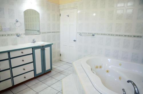 a white bathroom with a tub and a sink at Bascombe Apartments in Kingstown