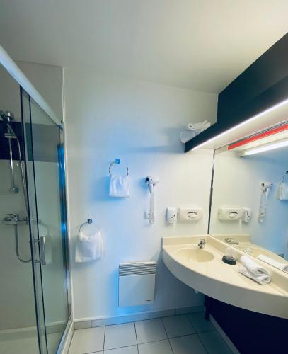 a blue bathroom with a sink and a shower at Hotel Air-lane in Saint-Léger-sous-Brienne