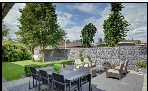 a patio with a table and chairs and a stone wall at LinZn vakantiehuis in Wuustwezel