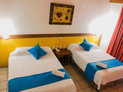 a hotel room with two beds with blue pillows at Hotel Pez Vela in Manzanillo