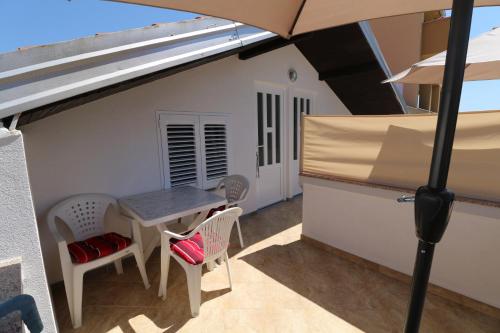 a patio with a table and chairs and an umbrella at Studio apartmani Rajlić in Nin