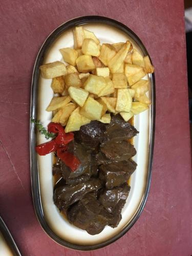 a plate of food with meat and potatoes on a table at La Casona de Mestas in Ponga