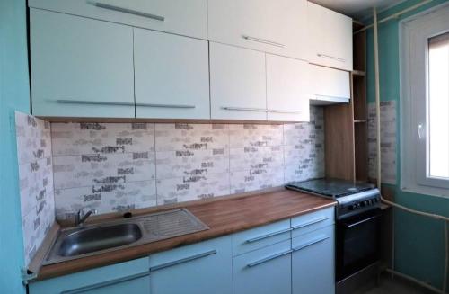 a kitchen with white cabinets and a sink at Panorama apartment near Szeged Plaza in Szeged