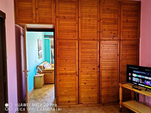 a wooden closet in a room with a television at Ξένιος Ζευς Ηλιακτής. Χώρος Χαλάρωσης & Ξεκούρασης in Áyios Yeóryios