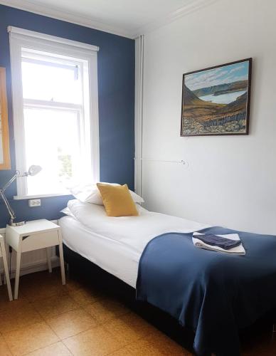 a bedroom with a bed with blue walls and a window at Refurinn Reykjavik Guesthouse in Reykjavík