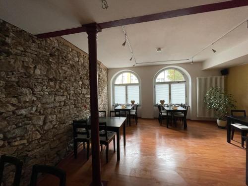 a dining room with tables and chairs and a stone wall at Pension Altstadt in Weimar