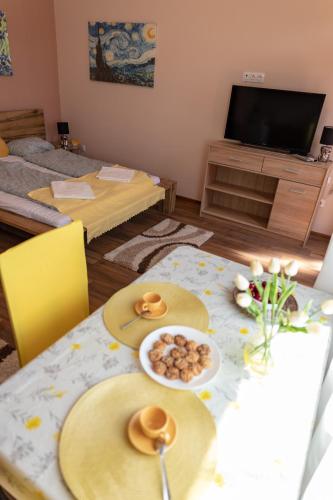 a living room with a table with plates of food on it at Linett Apartman in Hajdúszoboszló