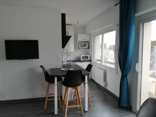 uma pequena cozinha e sala de jantar com mesa e cadeiras em Appartement proche mer et plage em Douarnenez
