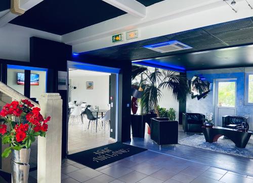 a dining room with a table and a vase of red flowers at Hotel Air-lane in Saint-Léger-sous-Brienne