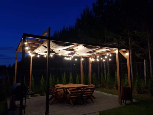 a table and chairs under a pergola with lights at Forest House - Domy Mazur in Regiel