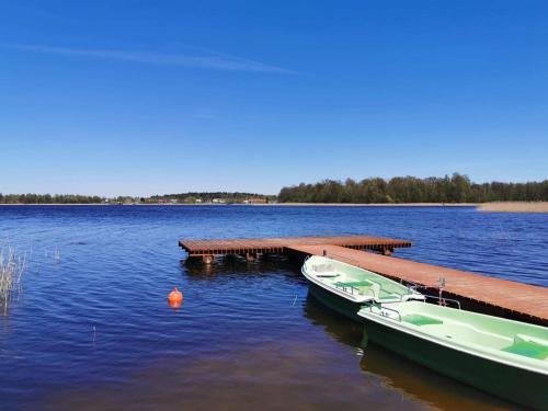 a boat is docked at a dock on a lake at Forest House - Domy Mazur in Regiel