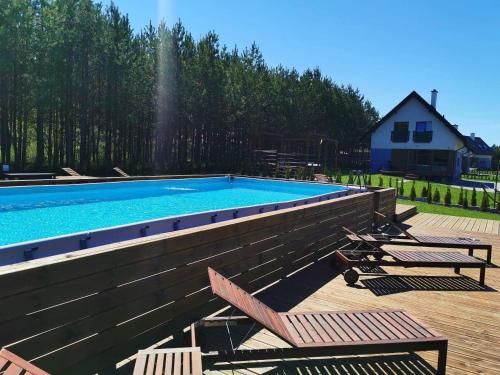 a swimming pool with two chairs and a house at Forest House - Domy Mazur in Regiel
