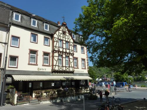 ein großes weißes Gebäude mit einem Restaurant davor in der Unterkunft Hotel am Markt Sankt Goar in Sankt Goar