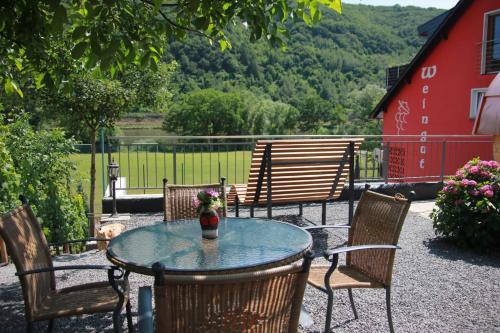 a table with chairs and a vase of flowers on a patio at Weingut Schumacher - mit privatem Saunabereich in Sankt Aldegund