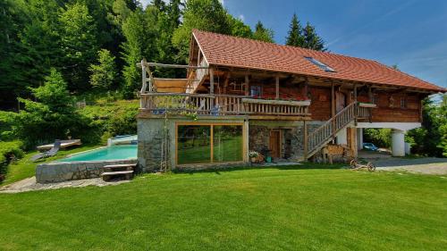 a log house with a swimming pool in front of it at Chalets Toplak in Sveti Duh na Ostrem Vrhu
