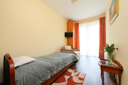 a bedroom with a bed and a chair and a window at Balazs Villa in Balatonfüred