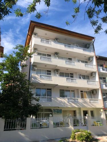 an apartment building with white balconies and a tree at Borko Guest House in Primorsko