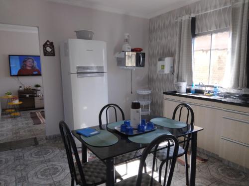 a kitchen with a table with chairs and a refrigerator at CASA TEMPORADA - PARA 05 PESSOAS in Trindade