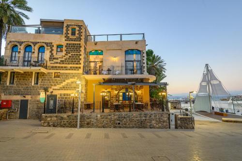 a yellow building with a balcony and a boat at Shirat Hayam Boutique Hotel in Tiberias