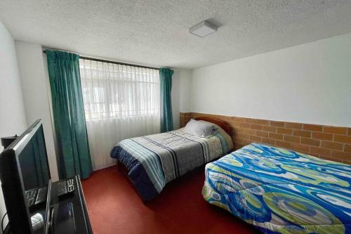 a bedroom with two beds and a television in it at La casa de los abuelos in Lasso