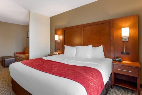 a hotel room with a large bed with a red blanket at Comfort Suites Knoxville North in Knoxville