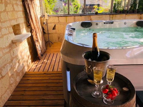 - une bouteille de champagne dans une baignoire avec 2 verres dans l'établissement Maison de Lavande, à Ranton
