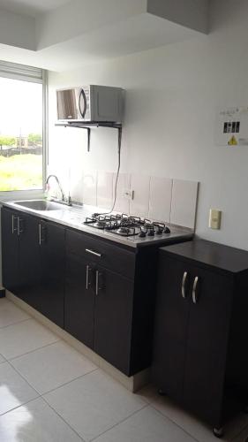 a kitchen with black cabinets and a stove top oven at Economico Apto a 3' al Parque del Café in Quimbaya