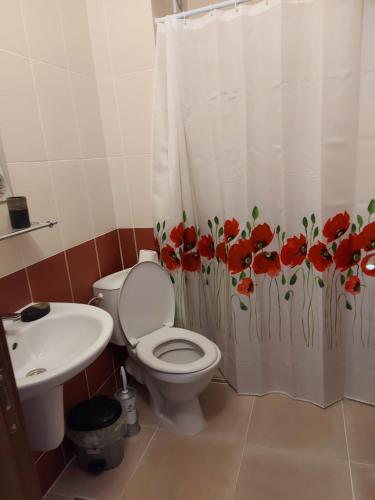 uma casa de banho com um WC, um lavatório e uma cortina de chuveiro em До морето em Burgas