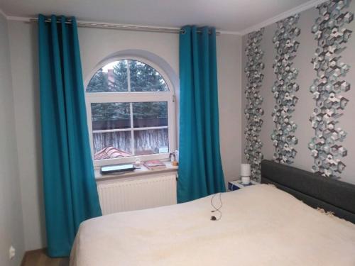 een slaapkamer met een bed met blauwe gordijnen en een raam bij Apartament Mazurski nad Węgorapą in Węgorzewo