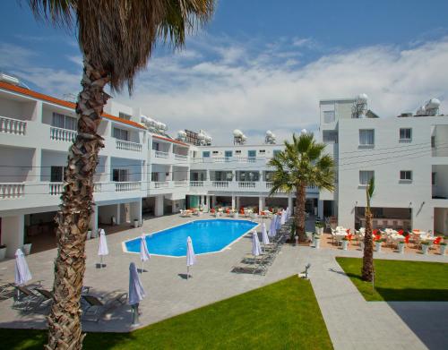 Blick auf ein Hotel mit einem Pool und Palmen in der Unterkunft Princessa Vera Hotel Apartments in Paphos City