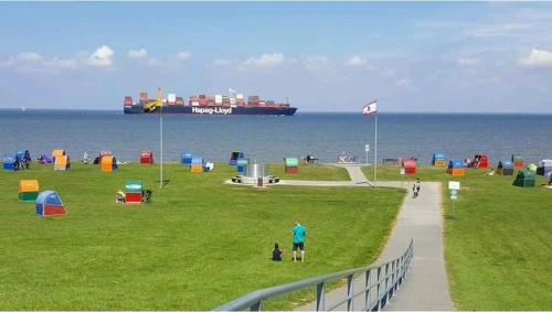 a large container ship in the ocean with a person and a person walking sidx sidx at Tinyhouse am Fluss in Otterndorf