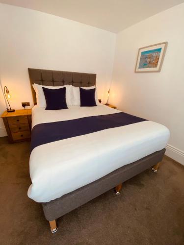 a bedroom with a large bed with blue and white pillows at Carlton Guest Suites - Weymouth in Weymouth