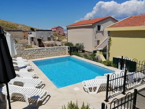 a swimming pool with lounge chairs next to a house at Family apartments Grguric in Pag