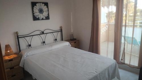 een slaapkamer met een wit bed en een raam bij ATICO DUPLEX UMA in Benicarló