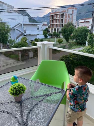 a little boy standing next to a table on a balcony at Apartments Pericic in Sutomore