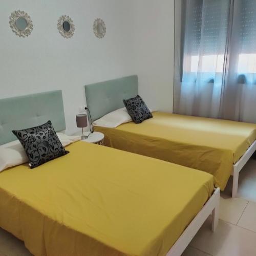 two beds in a room with yellow sheets at Apartamento en el centro in Reus