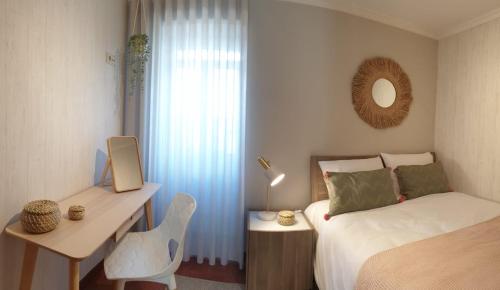 a bedroom with a bed and a desk and a mirror at Vivenda Oliveira - Alojamento Local in Lamego